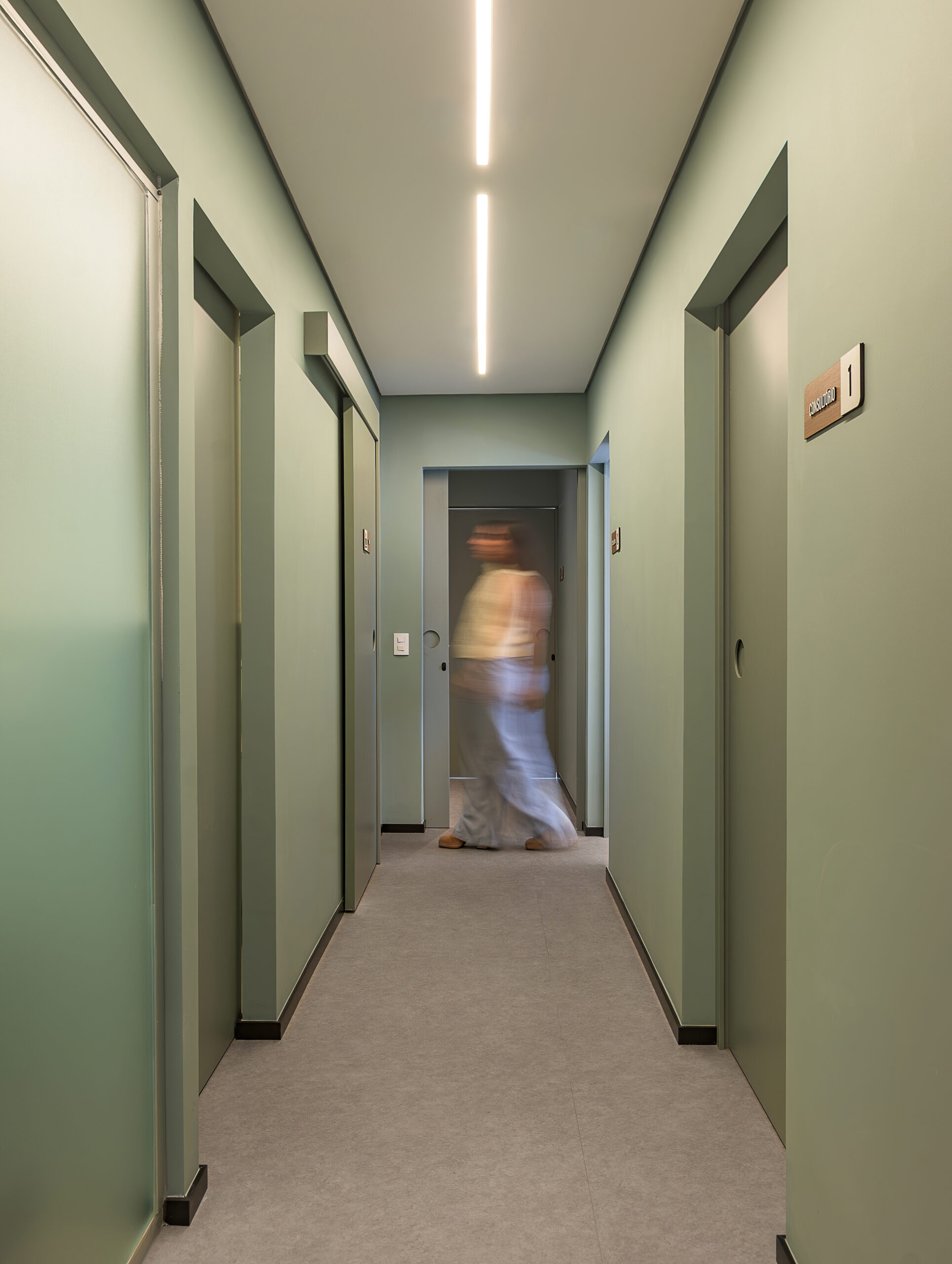 Corredor verde de acesso aos consultórios com iluminação linear no forro do consultório de cardiologia — projeto e obra da MWARQ