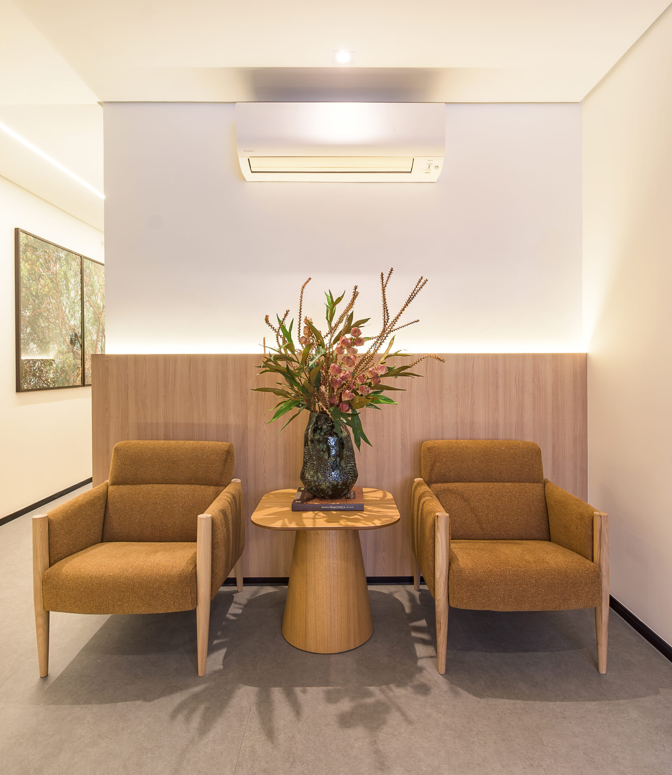 Poltronas e mesa lateral em madeira na área de espera do consultório de cardiologia — projeto e obra da MWARQ